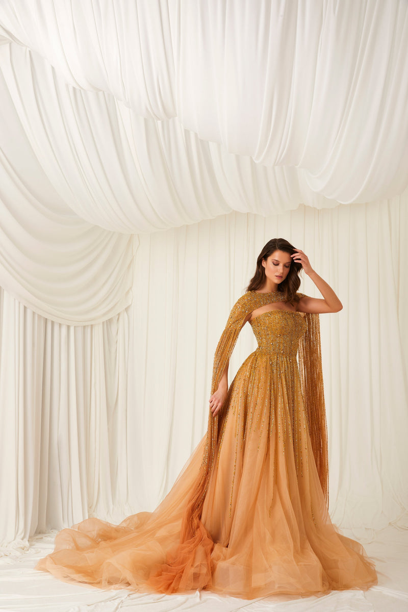 Li Beirut M1002 – Strapless Embellished Gold Ball Gown with Beaded Cape Overlay